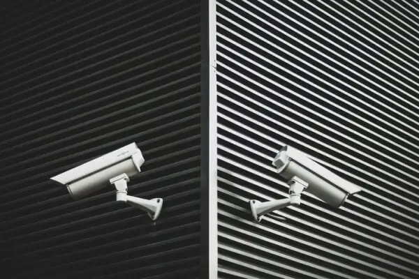 Security cameras mounted on a black building exterior for surveillance.