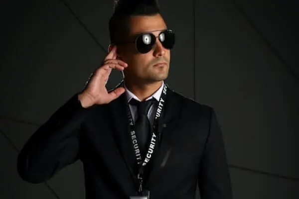 Security guard in black suit and sunglasses demonstrating vigilance and protection.